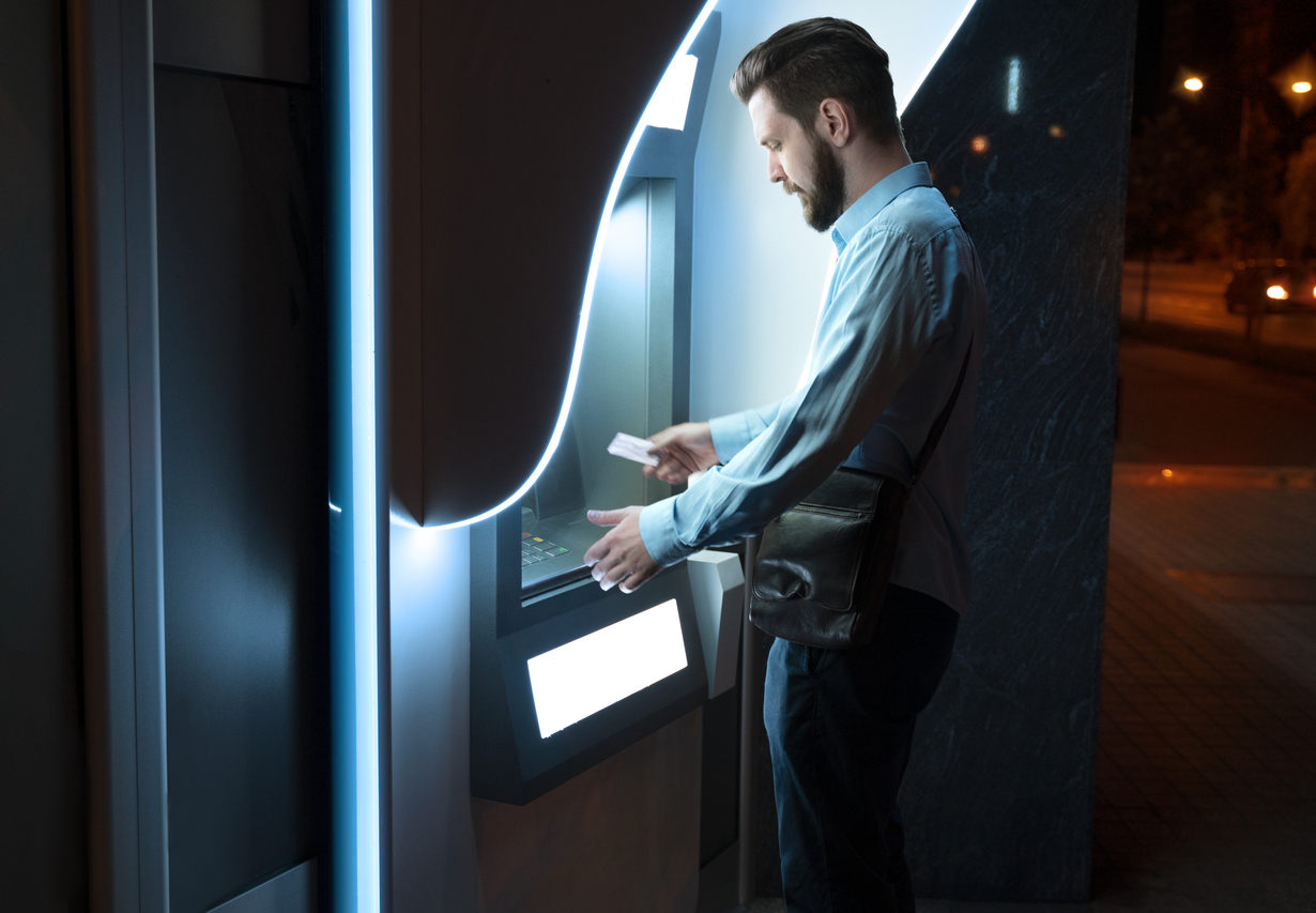 Business professional withdrawing cash from a modern ATM at night demonstrating real-world ATM usage in 2026